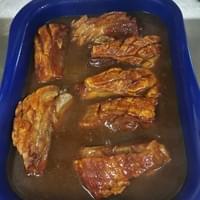 Ein blaues Tablett mit Fleisch und Soße auf einem Tisch.