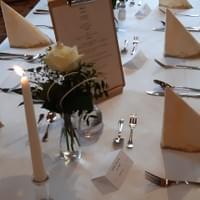 Ein für einen Hochzeitsempfang gedeckter Tisch mit Kerzen, Blumen und einem Menü.