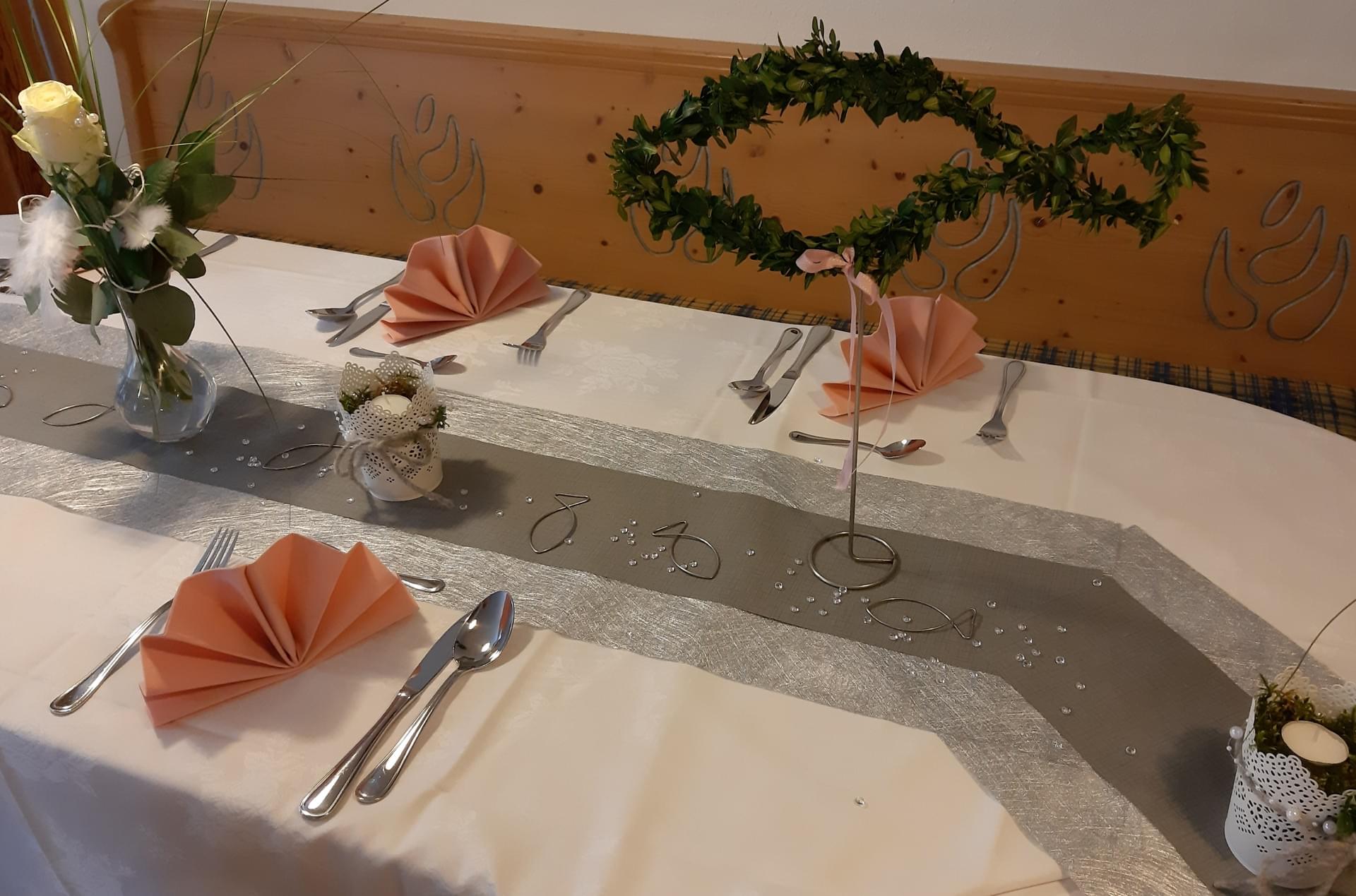 Ein Tisch mit einem silbernen Tischläufer und Blumen darauf