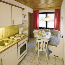 Eine Küche mit Tisch, Stühlen und Spüle.