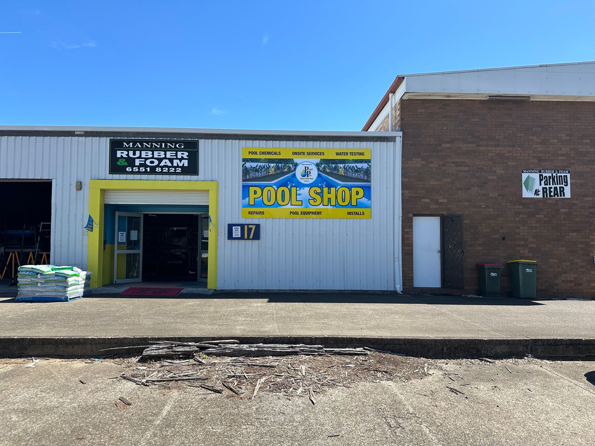 Pool shop storefront with a blue and yellow facade under a blue sky. — Manning Pools, Rubber & Foam In Taree, NSW
