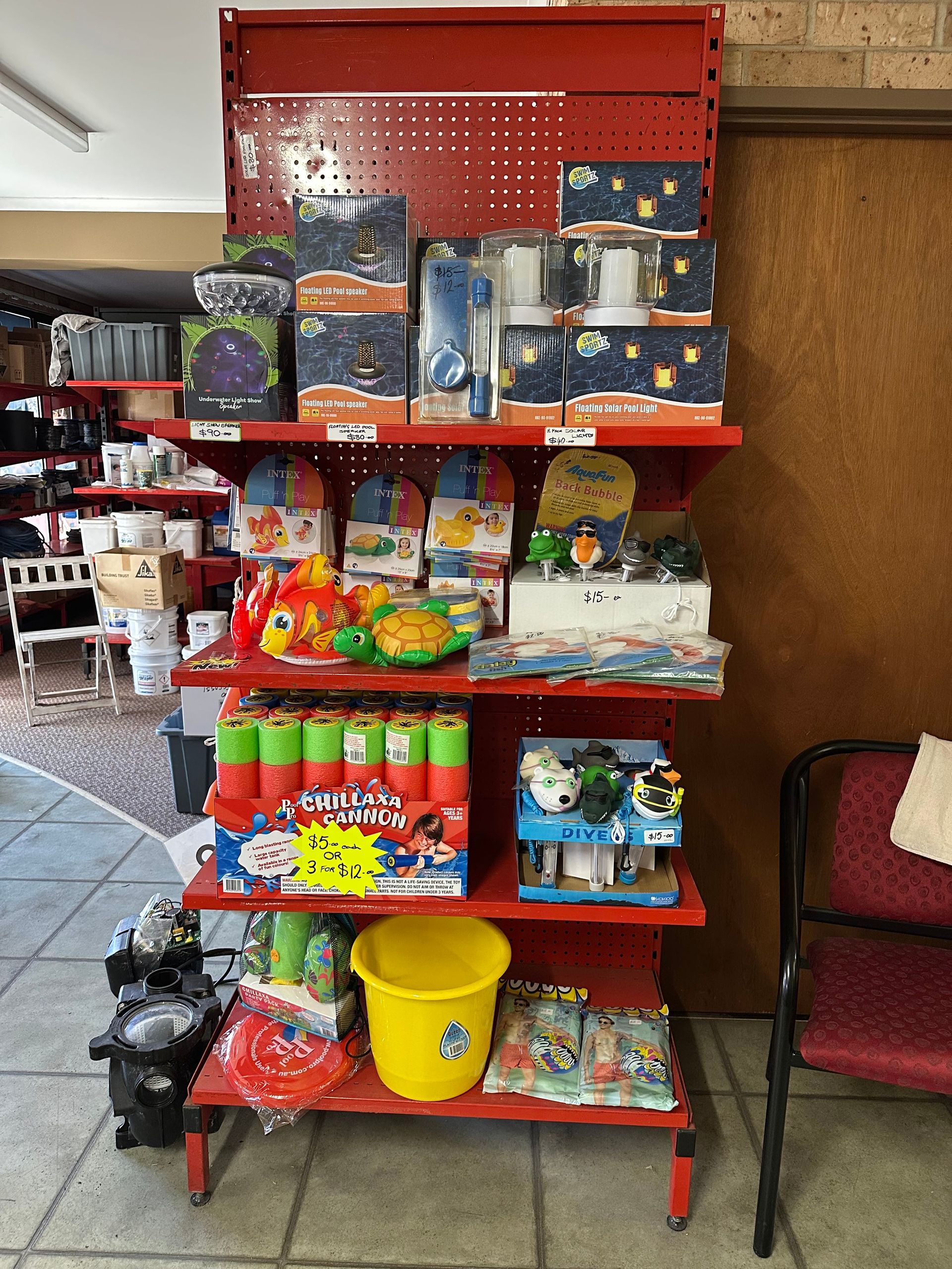 Red shelving unit stocked with various toys and supplies. — Manning Pools, Rubber & Foam In Taree, NSW