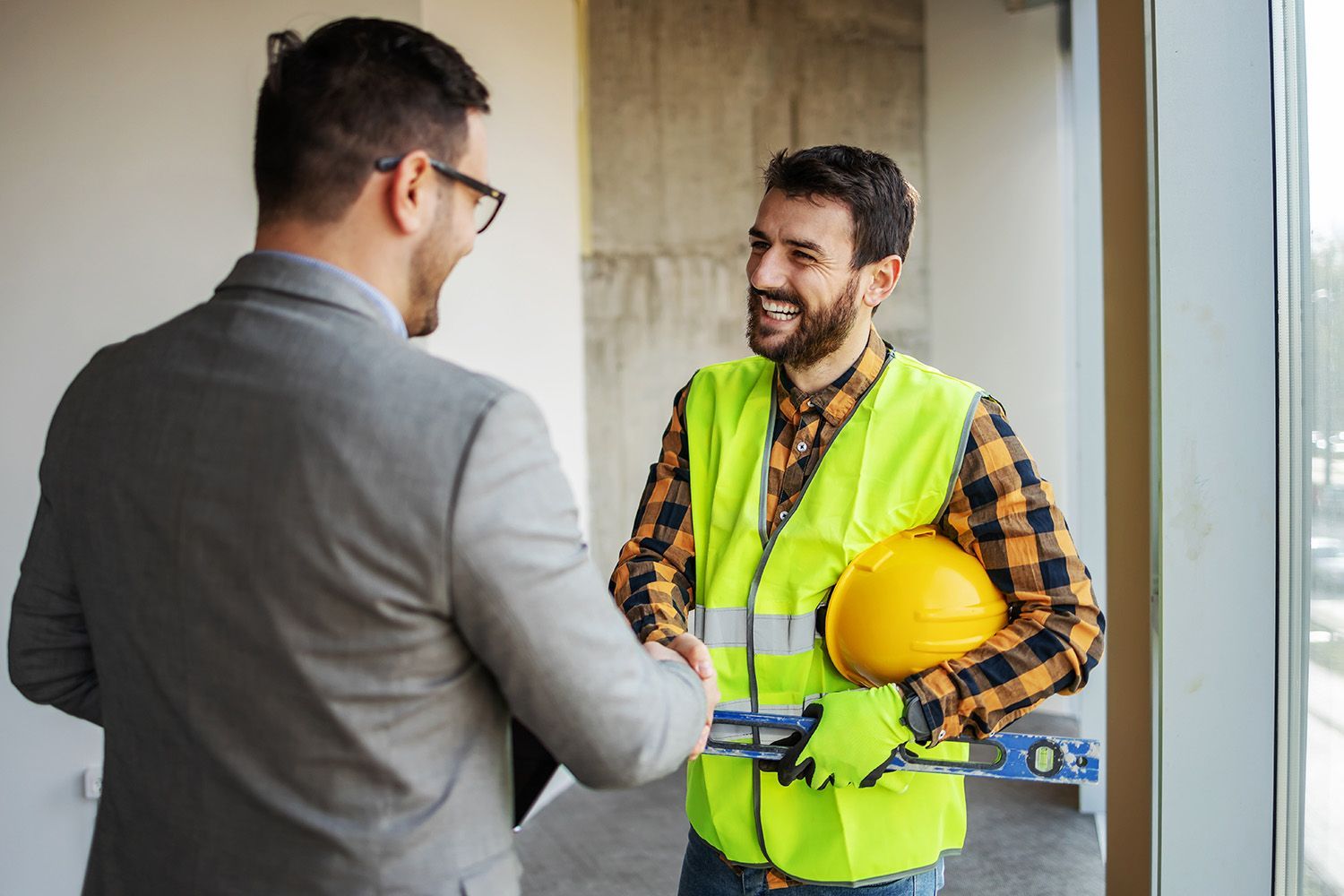 a man in a suit is shaking hands with a construction worker
