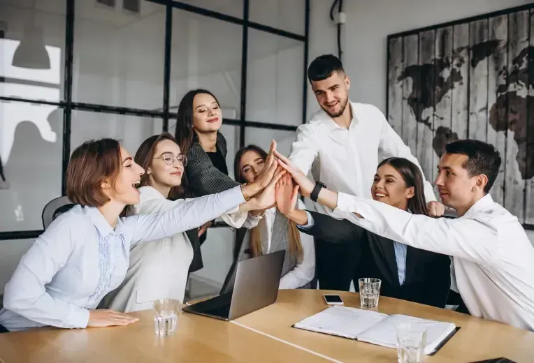 A group of people are giving each other a high five in an office.