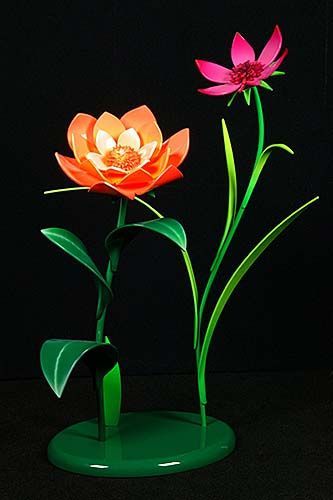 A red flower and a pink flower are in a green vase on a black background.