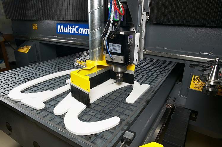 A machine is cutting a piece of foam into the shape of the letter c.