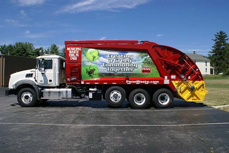 A garbage truck is parked on the side of the road