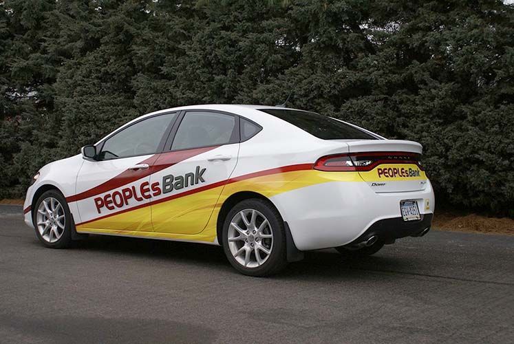 A white car with people 's bank written on the side is parked on the side of the road.