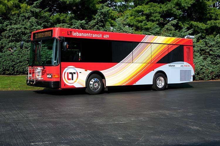 A red and yellow bus with the letter t on the side