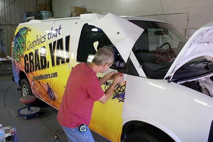 A man is working on a van that says grab ya !