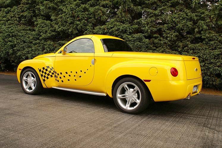 A yellow pickup truck is parked on the side of the road.