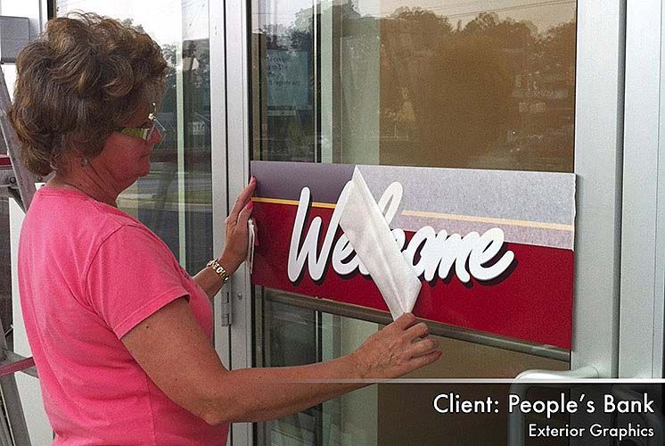 A woman is putting a welcome sign on a glass door