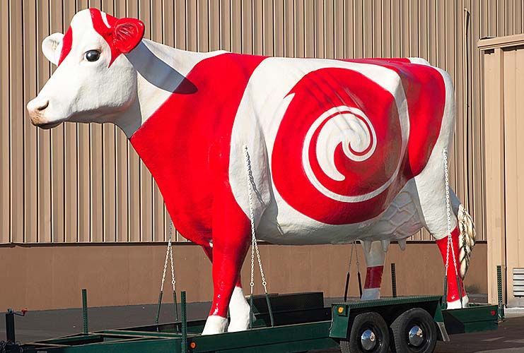 A statue of a red and white cow on a trailer