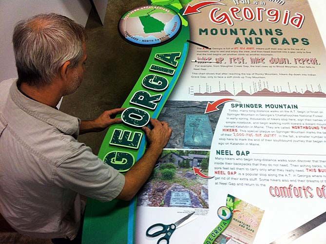A man is working on a sign that says georgia mountains and gaps