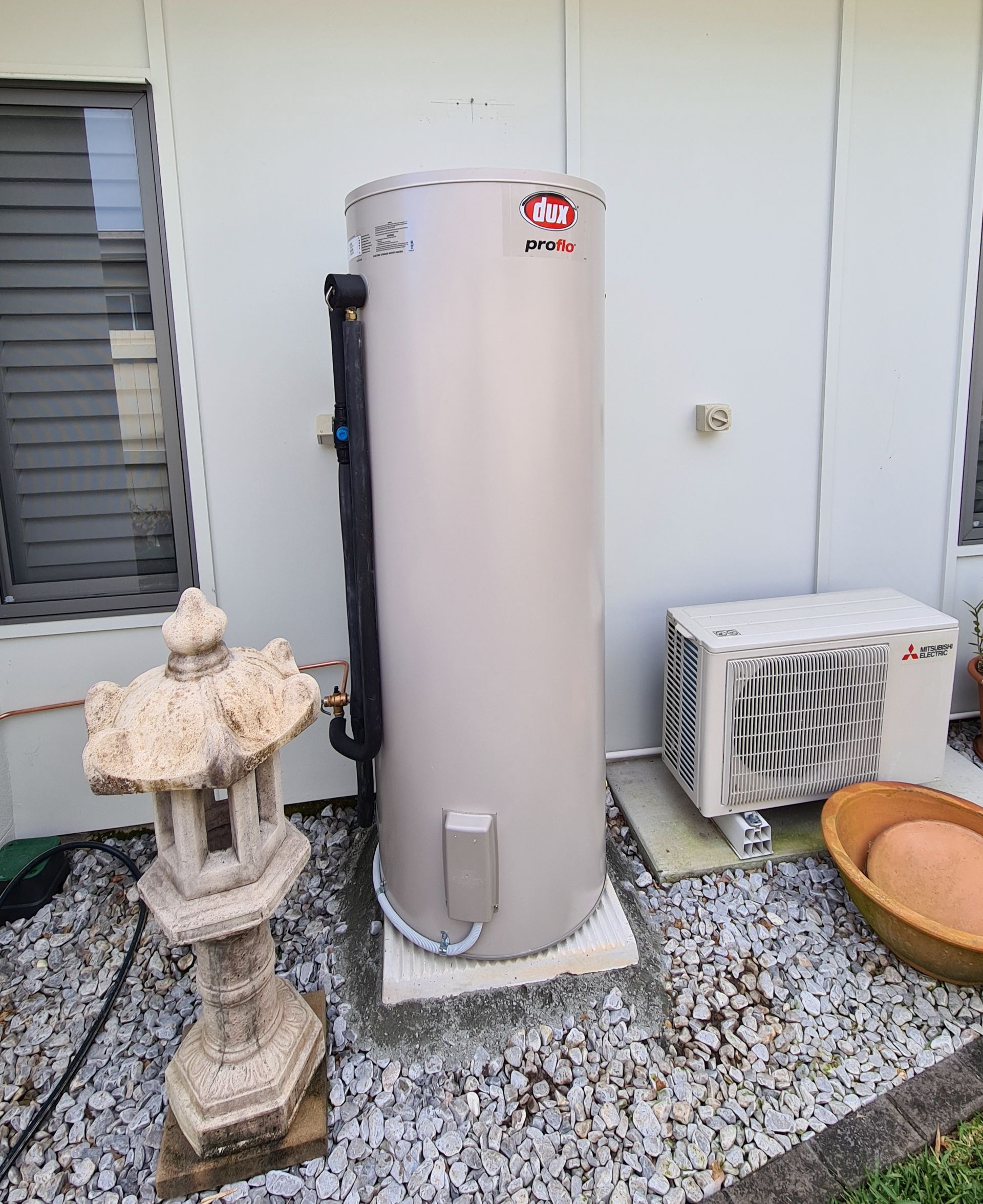 A Large White Water Heater Is Sitting on The Side of A Building — 24/7 HOT H2O in Valdora, QLD