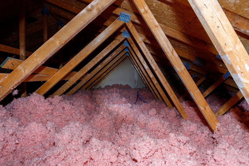 There is a lot of pink insulation in the attic of a house.