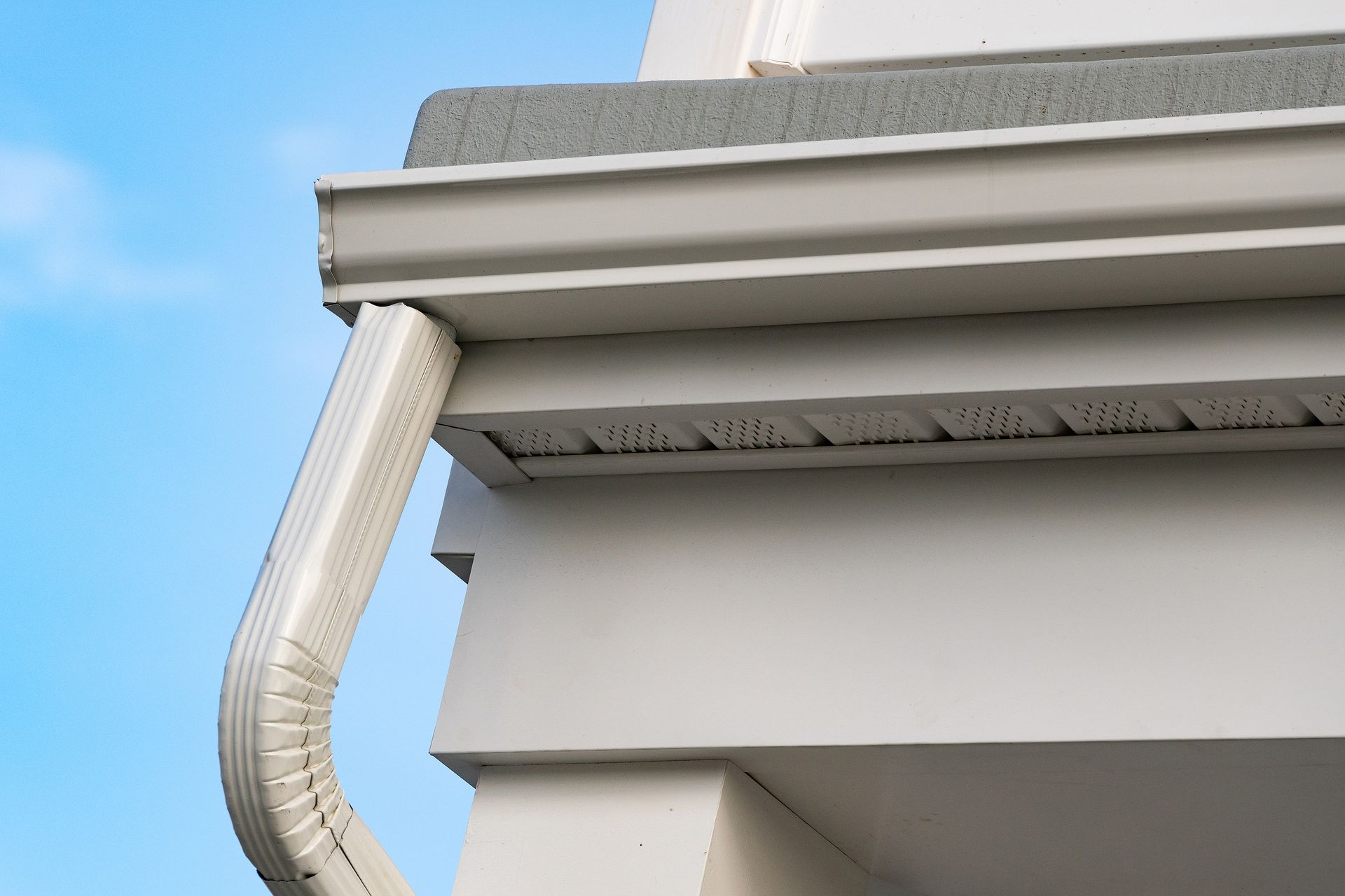 A close up of a white gutter on the side of a building.