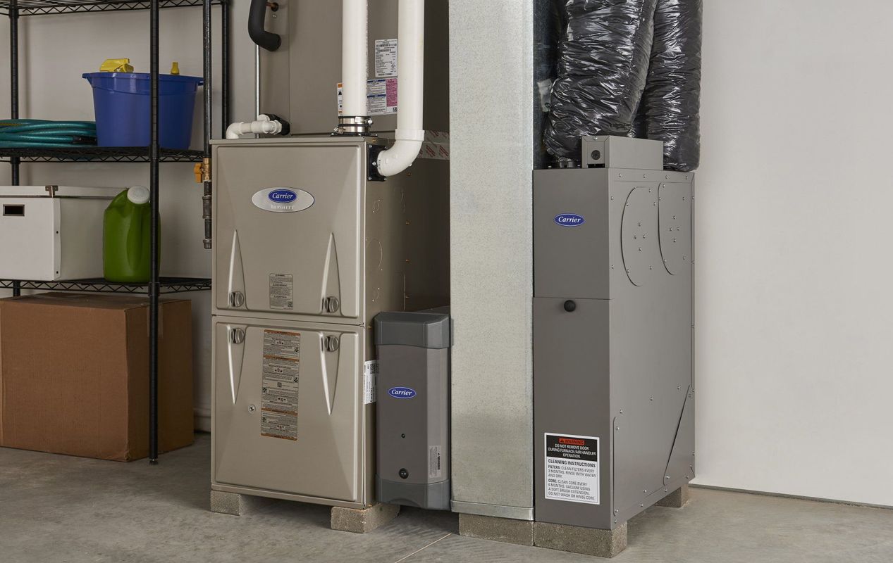 Two furnaces are sitting next to each other in a garage.