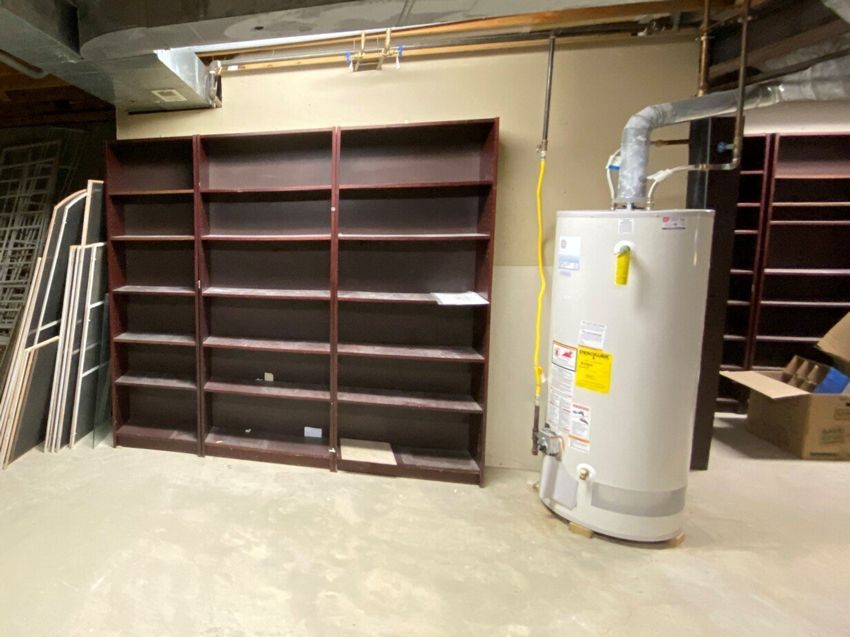 An empty room with shelves and a water heater