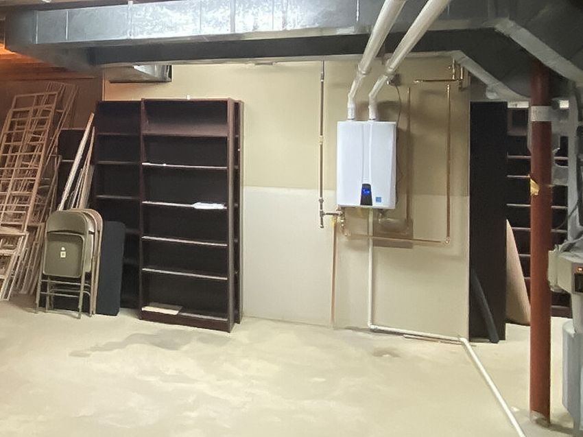 An empty basement with shelves and a water heater
