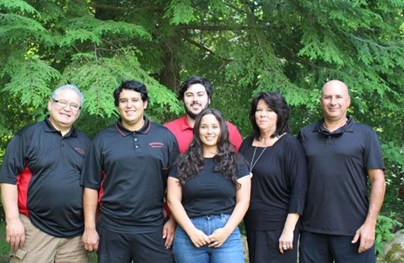 A group of people are posing for a picture in front of trees.