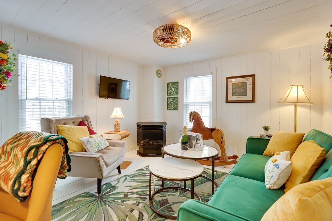 A cozy living room with a green sofa, a beige armchair, a round coffee table, and a wooden rocking horse on a rug.