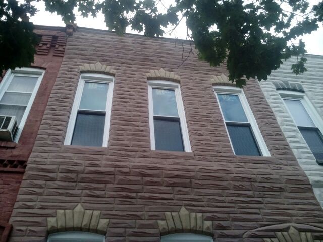 Brown brick building facade with three arched-top windows and stone detailing above and below.
