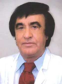 A man in a white coat and red tie is looking at the camera.