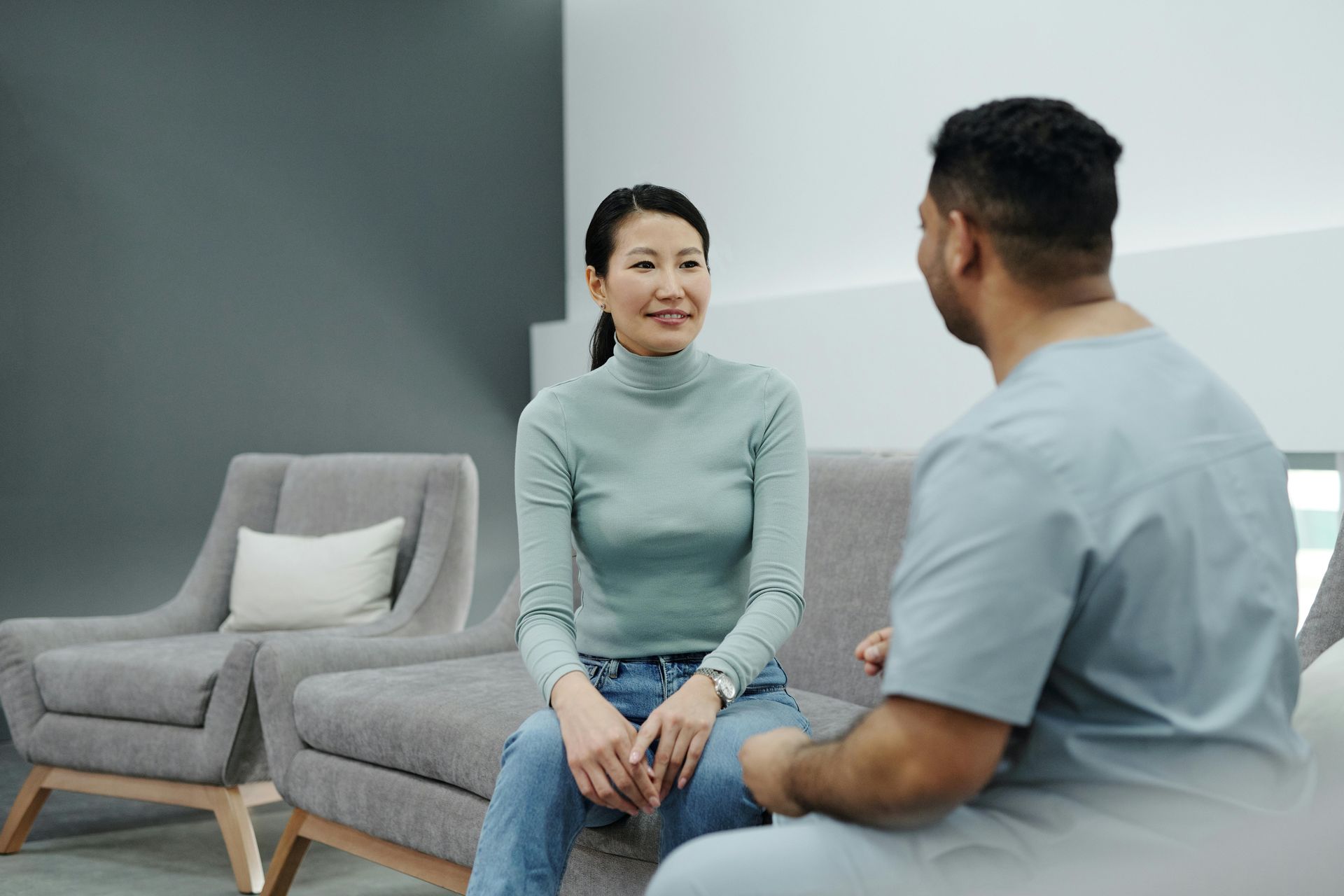 A man and a woman are sitting on a couch talking to each other.