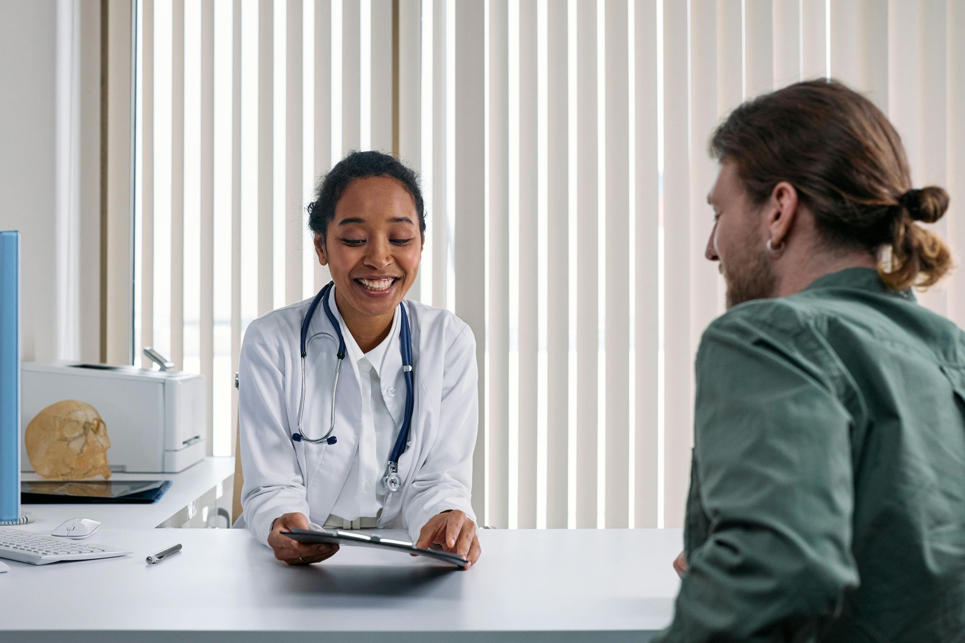 A doctor is talking to a patient at a desk in a hospital.