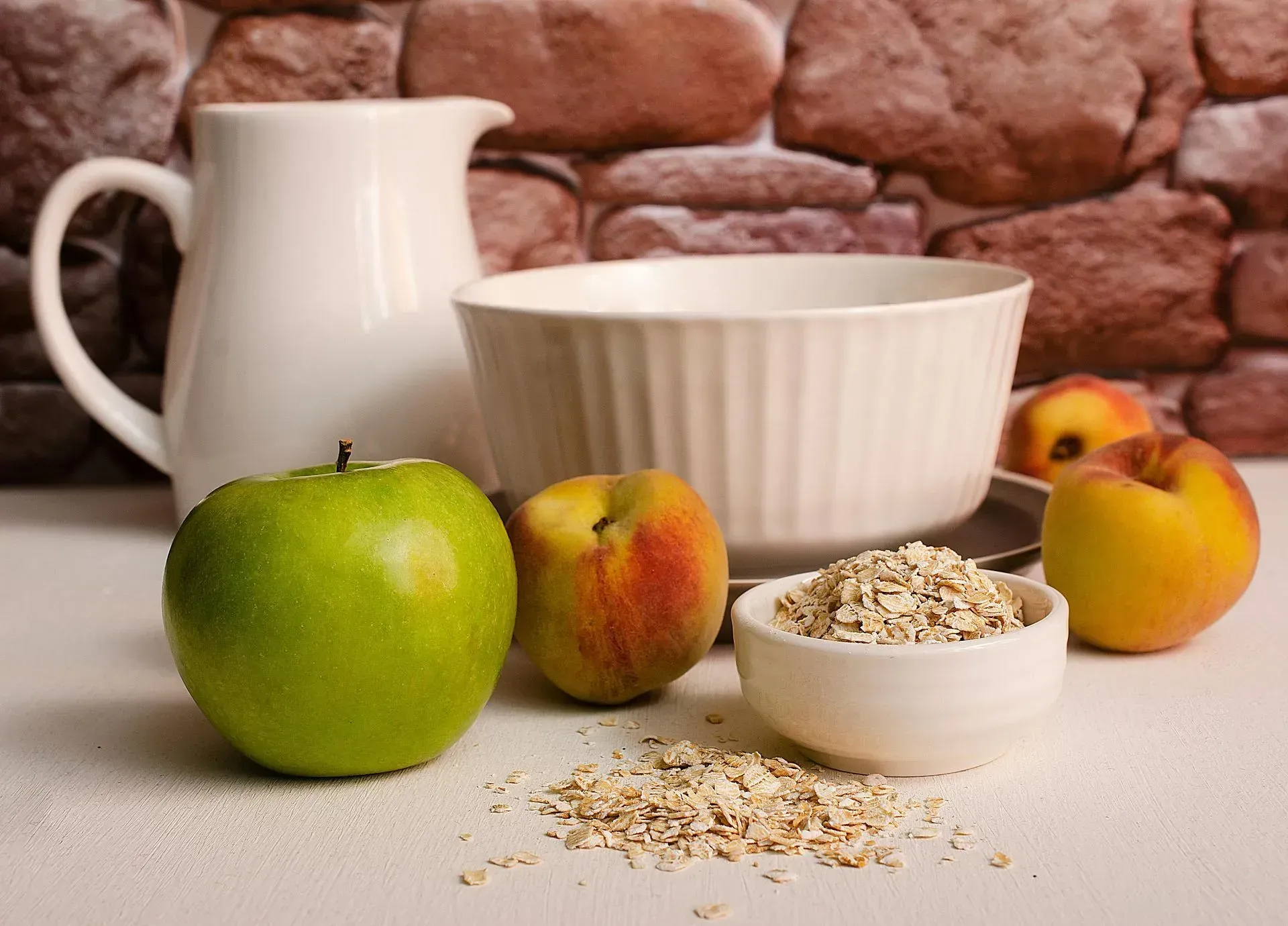 There is a bowl of oatmeal and apples on the table.
