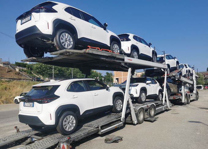 Carro attrezzi che carica un'auto bianca su una rampa a bordo strada, vista ravvicinata.
