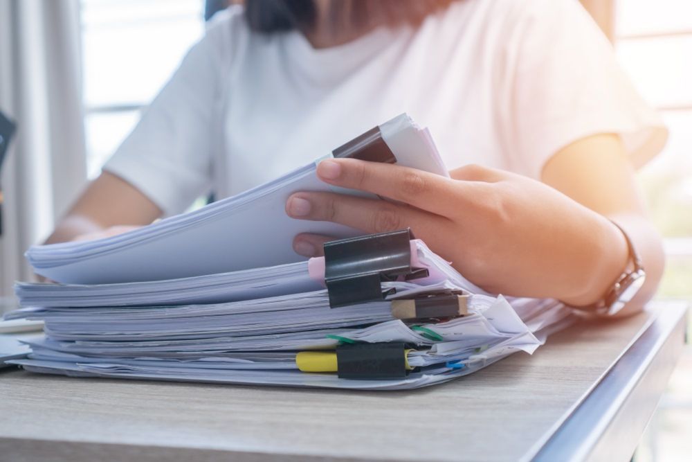 A Woman is Sitting at a Desk Holding a Legal Papers — Repo Busters Wyong In Wyong, NSW