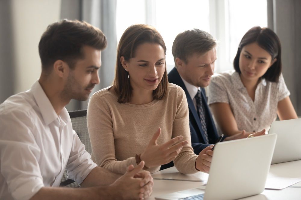 A Group of People Are Sitting at a Table Looking at a Laptop Computer — Repo Busters Wyong In Central Coast, NSW