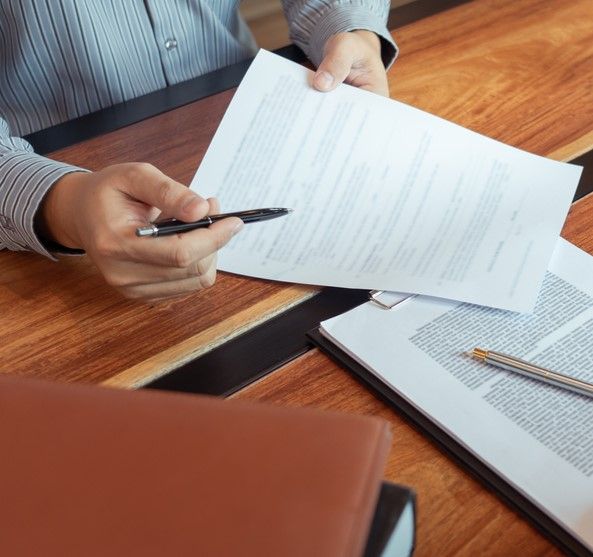 A Man is Holding a Pen Over a Piece of Paper — Repo Busters Wyong In Sydney, NSW