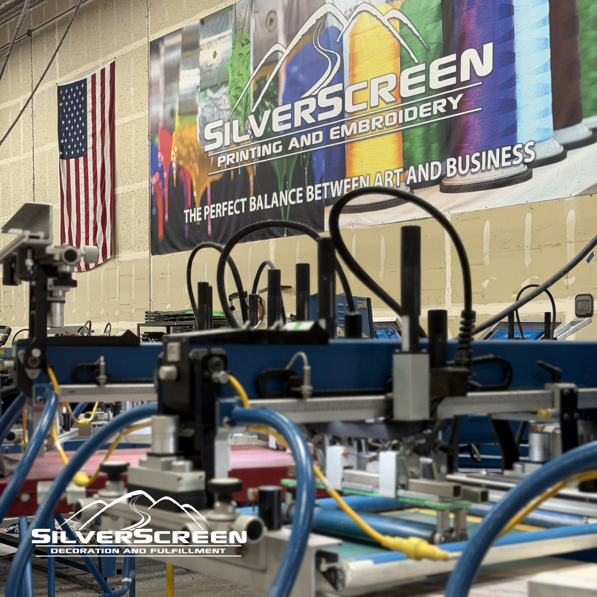 Silkscreen printing workshop with blue machinery and a large Silverscreen banner on the wall