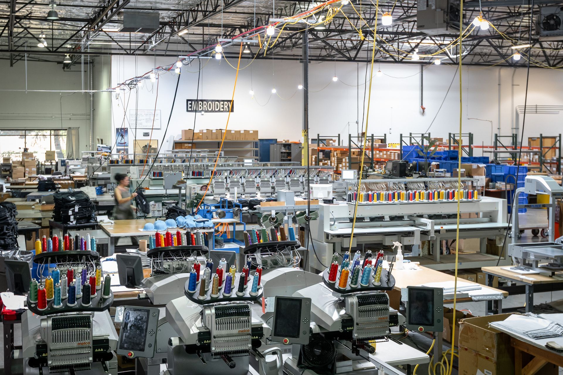Interior of a large factory floor with multiple sewing machines and colorful thread spools.