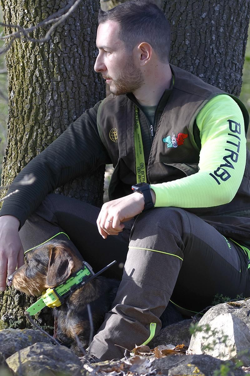 Un uomo è seduto accanto a un cane che indossa un collare verde.