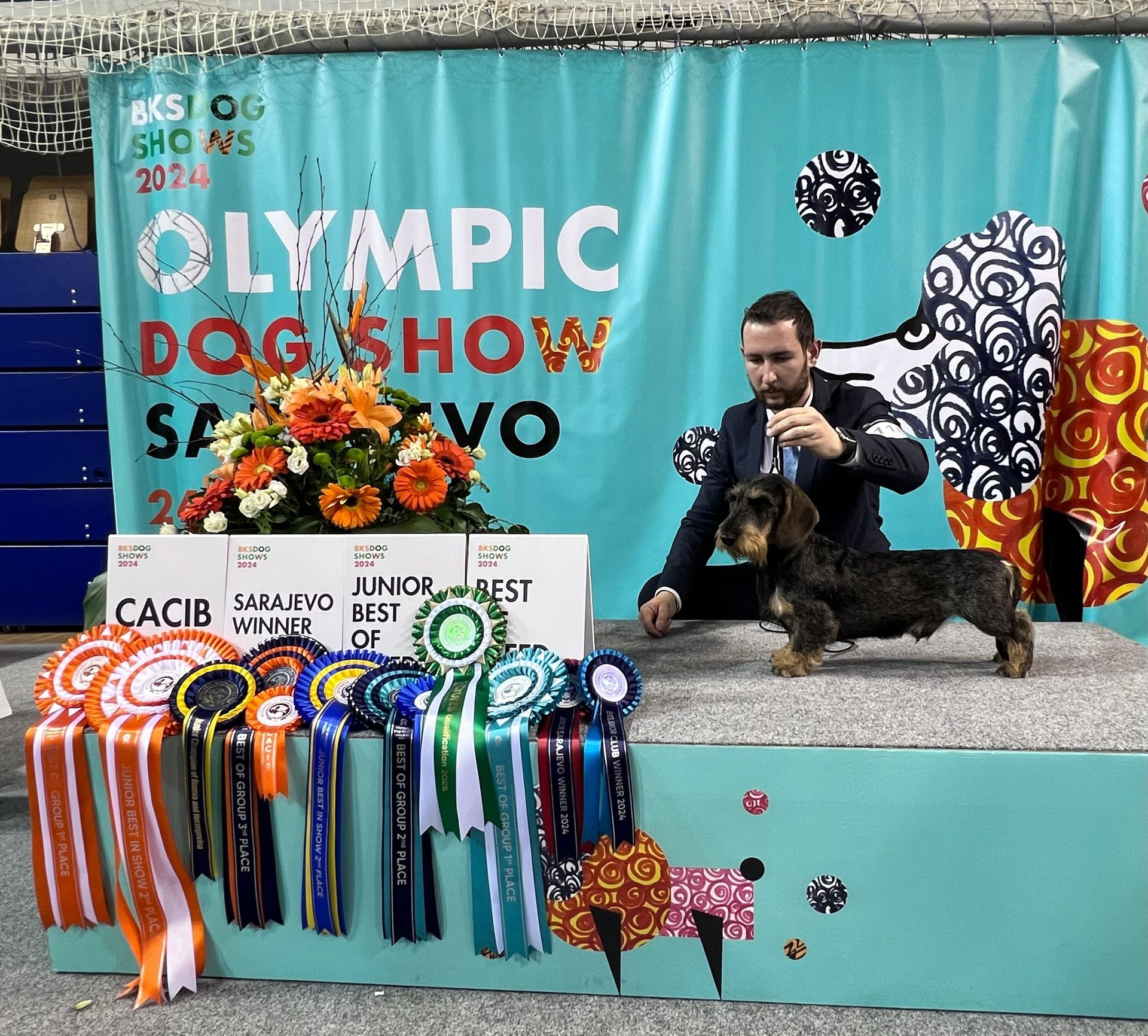 Un uomo e un cane sono in piedi su un palco durante l'esposizione canina olimpica