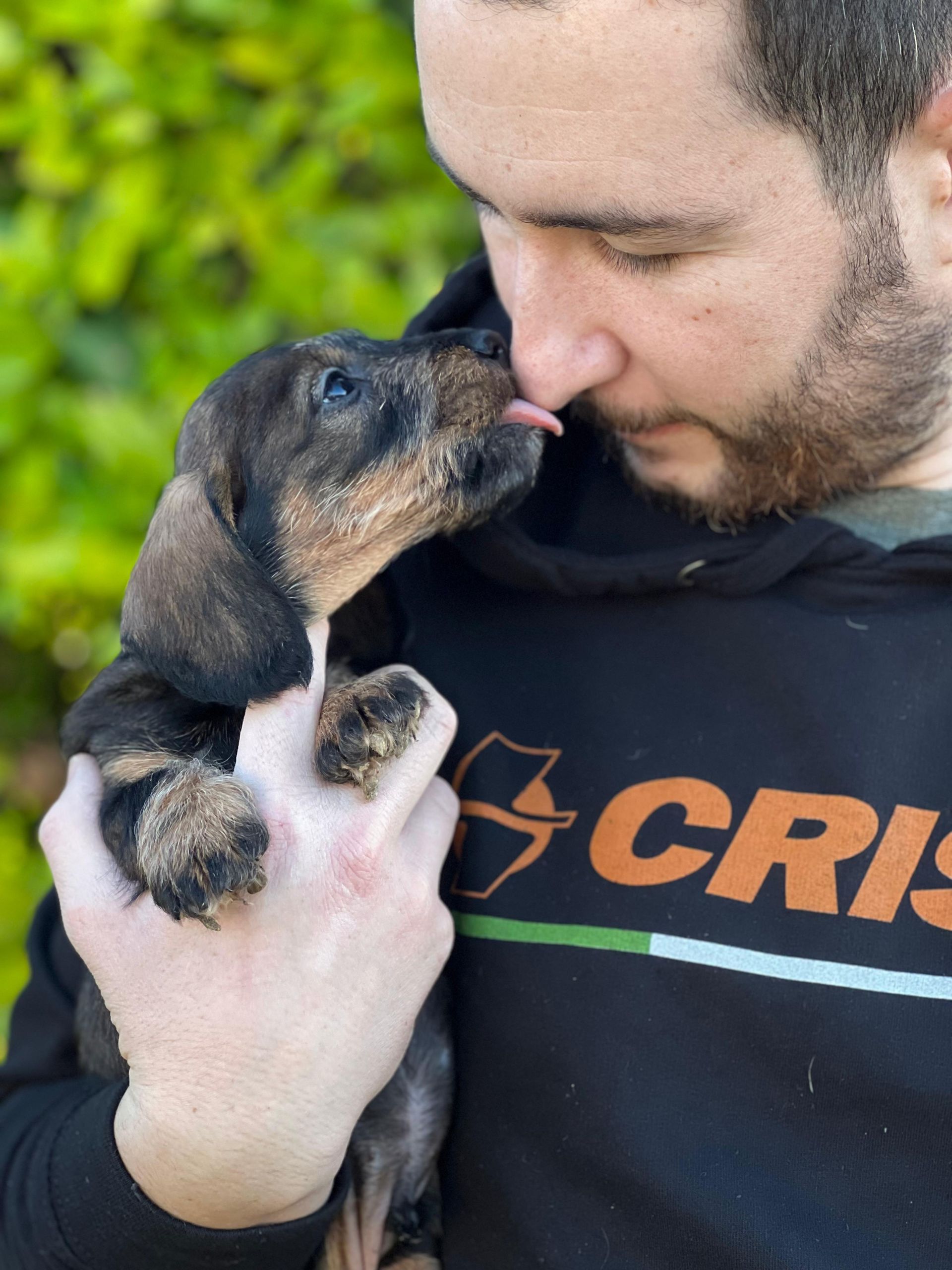 Un uomo che indossa una felpa con cappuccio anti-crisi tiene in braccio un cucciolo