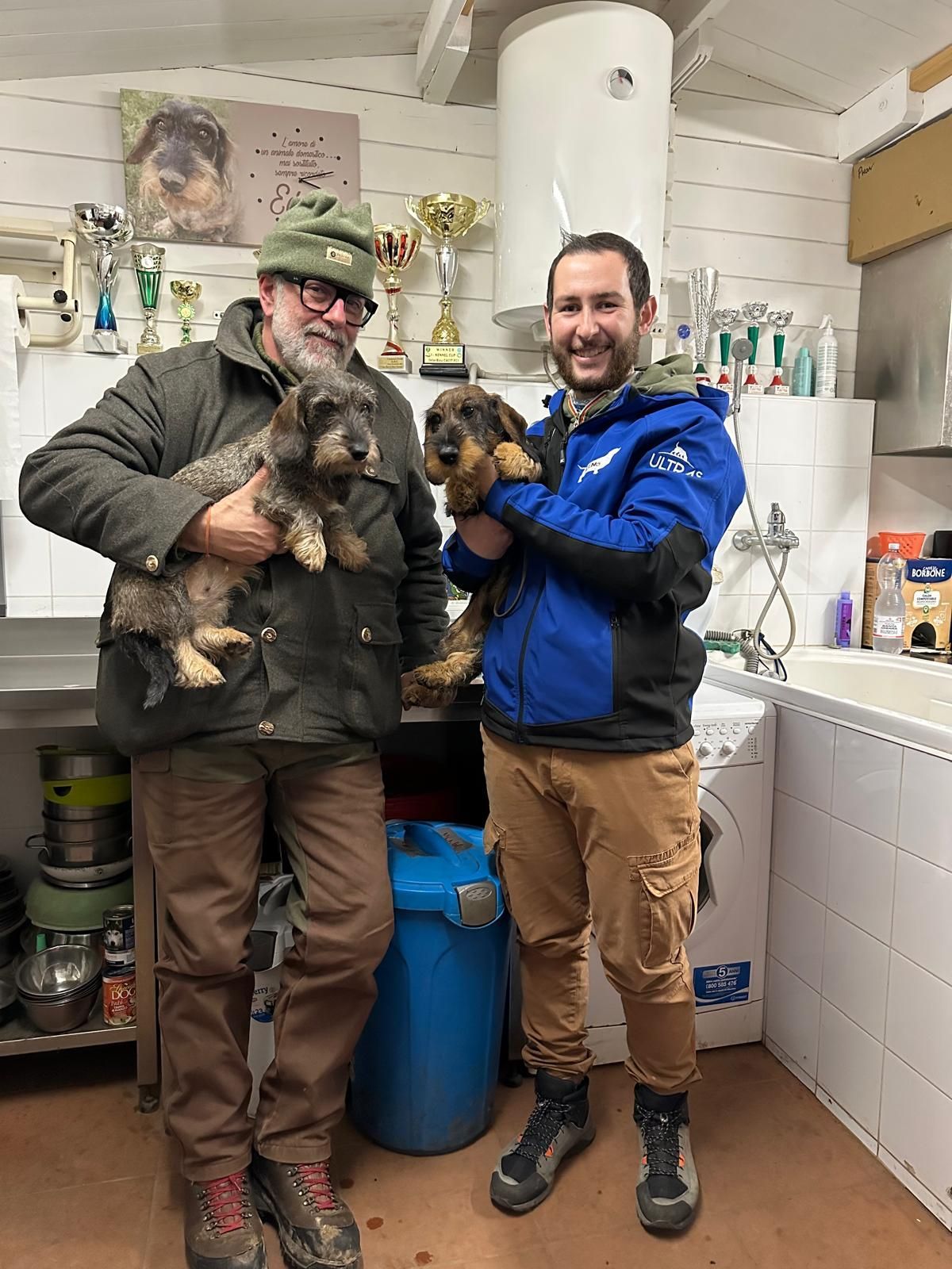 Due uomini sono in piedi uno accanto all'altro e tengono in braccio due cani.