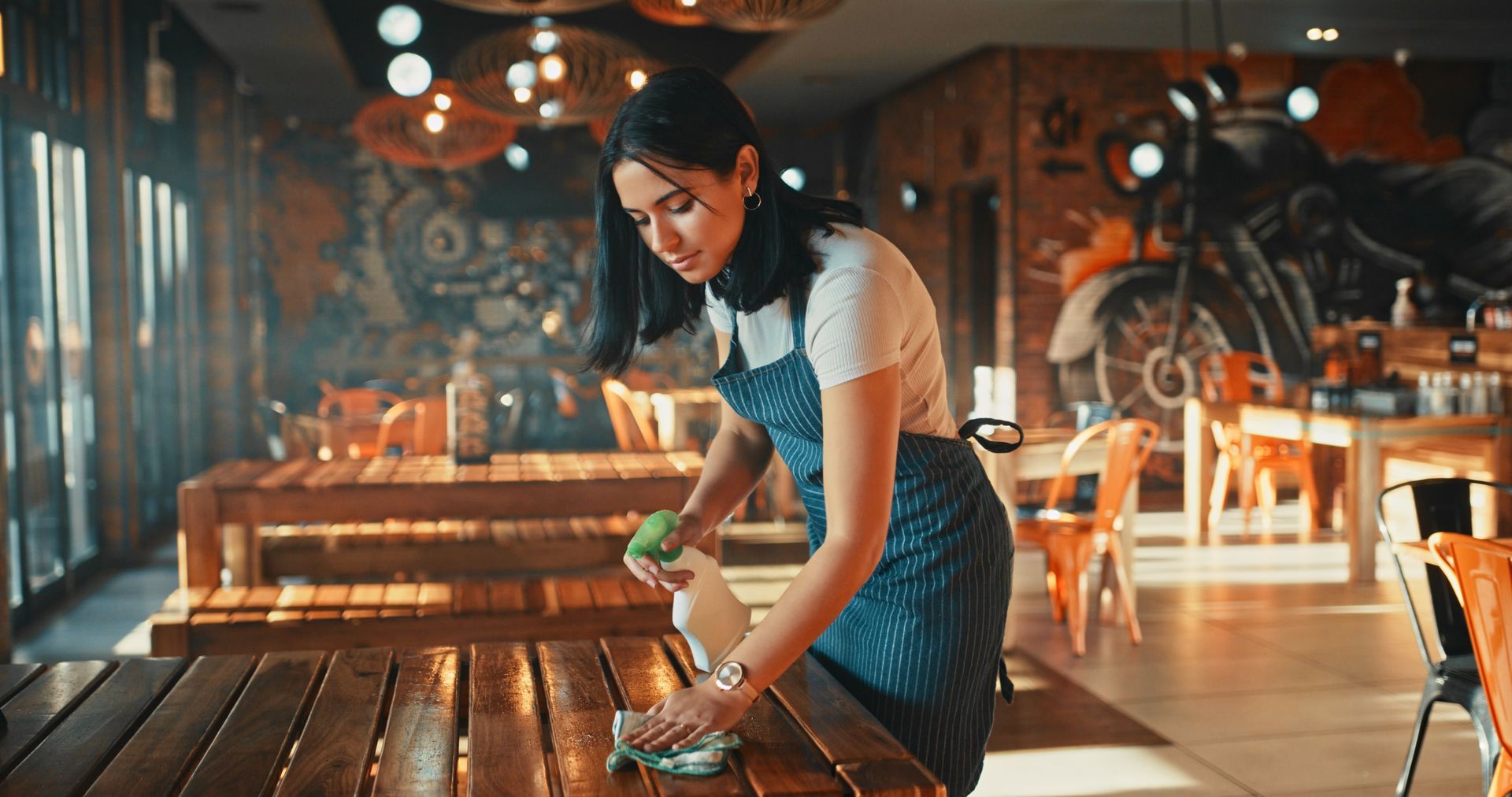 A Young Woman Is Disinfecting The Table In The Restaurant - Toronto, ON - Optimal Janitorial Restoration Services LTD