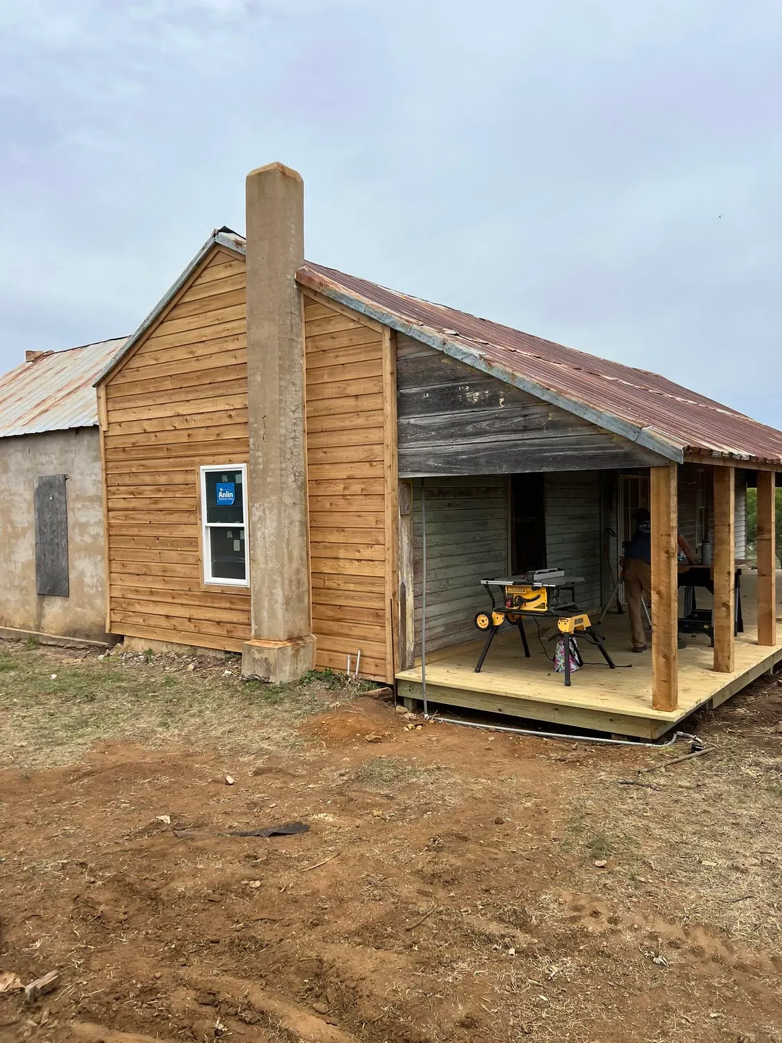 House under renovation with new wooden siding, porch, and chimney.