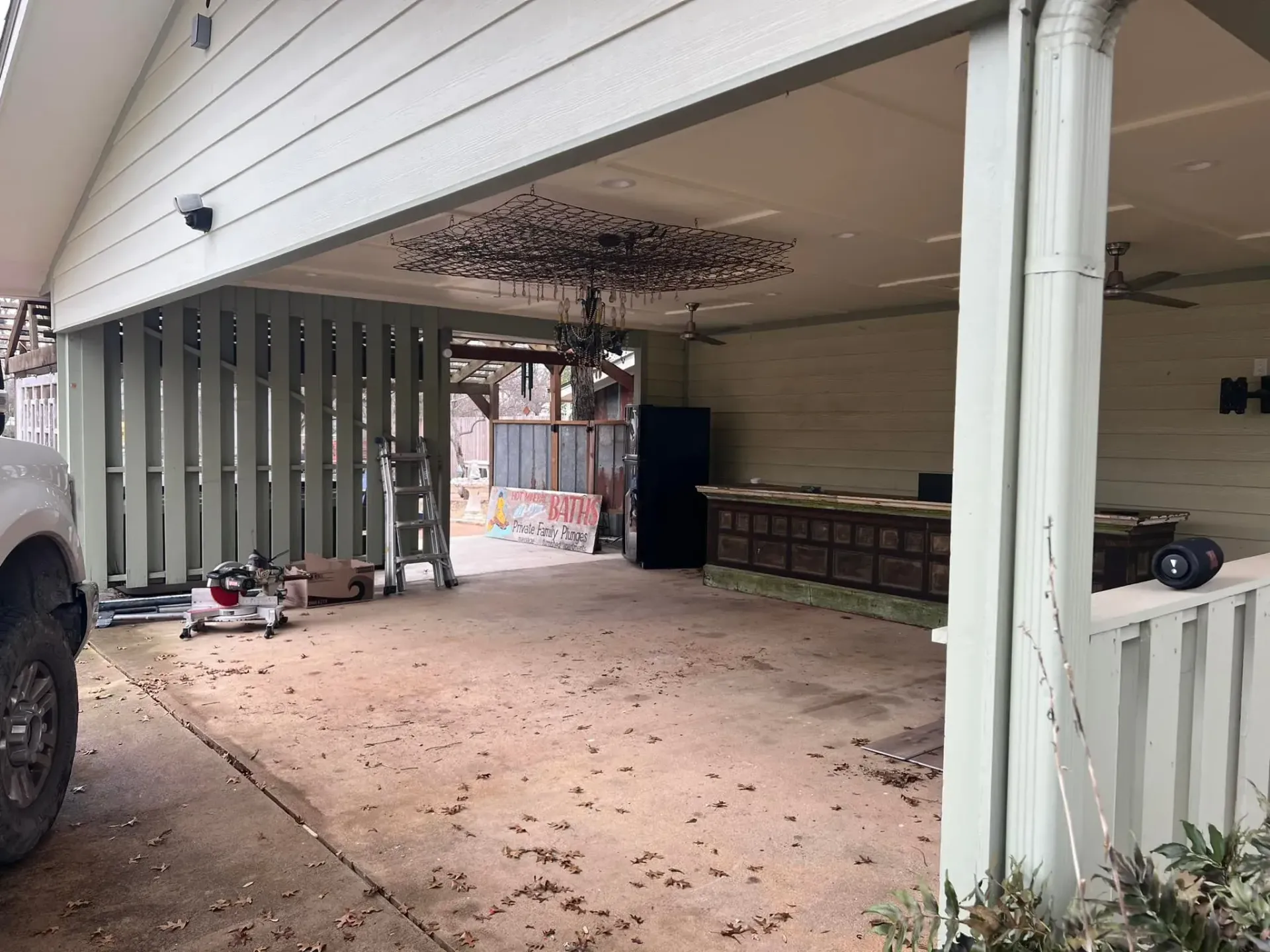 A covered outdoor space with vertical supports, a chandelier, and a bar area.