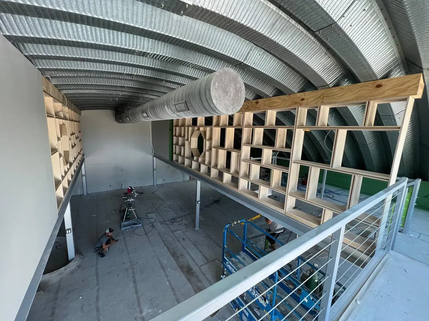 Interior view of a building under construction. A wooden structure is built in front of a metal arched ceiling.