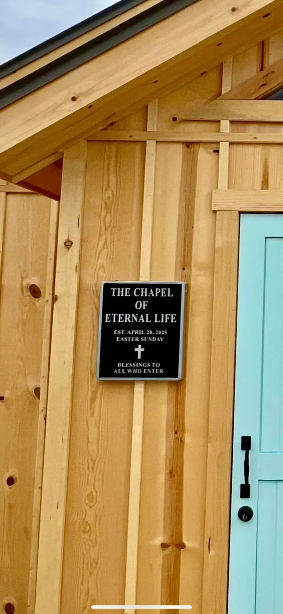 Sign on a wooden building with a teal door.