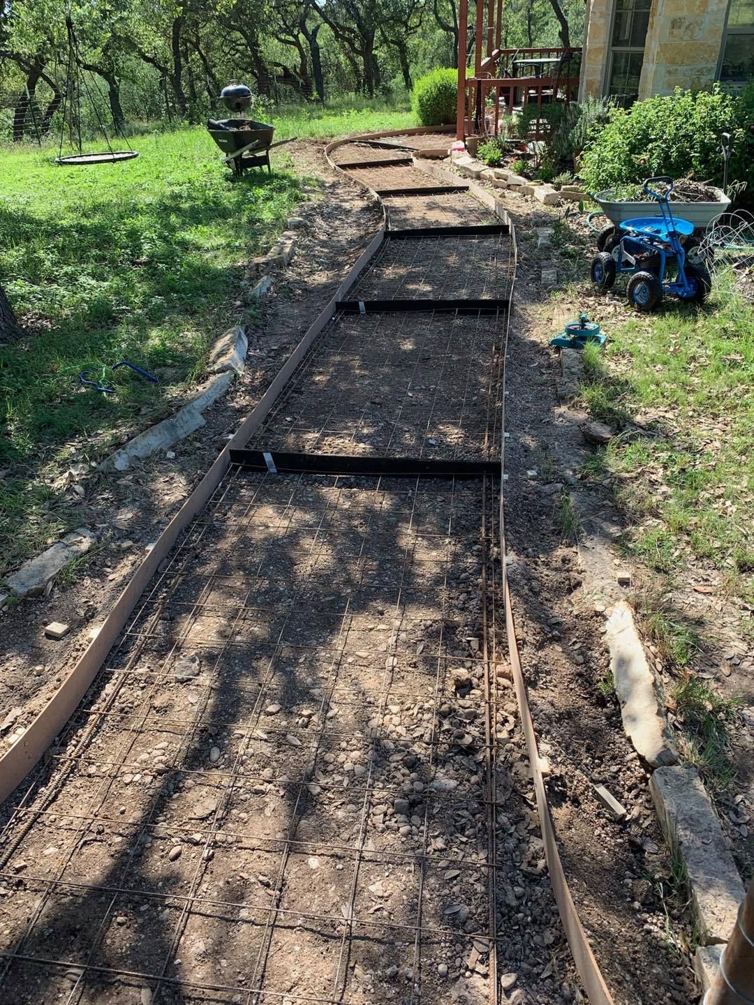 Pathway under construction with metal edging and concrete reinforcement.