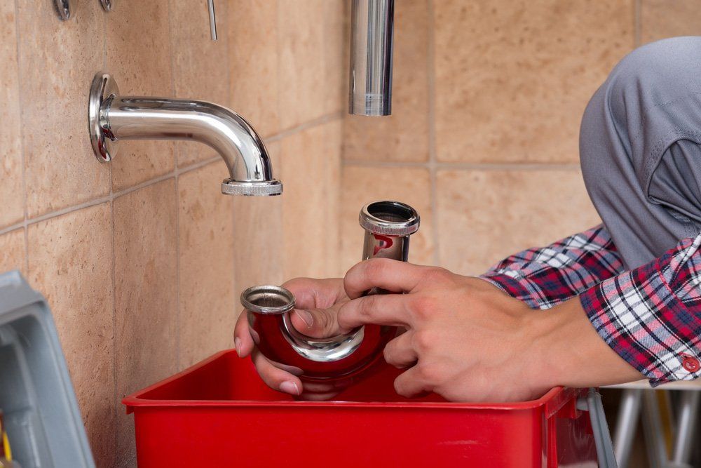 Plumber Fixing Sink In Bathroom — Plumbers in Highfields, QLD