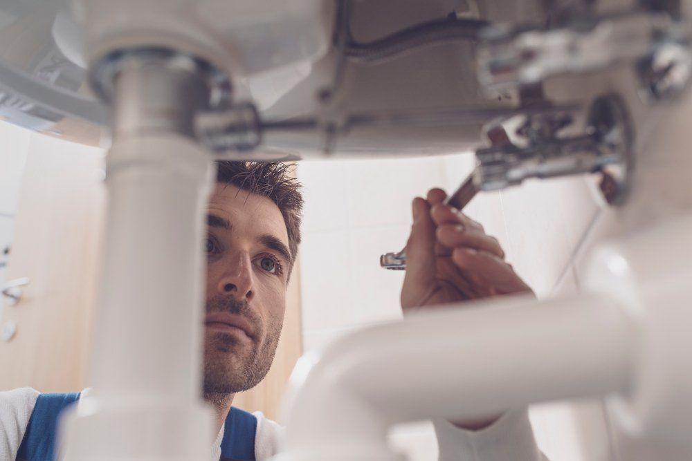 Professional Plumber Fixing a Sink — Plumbers in Harlaxton, QLD