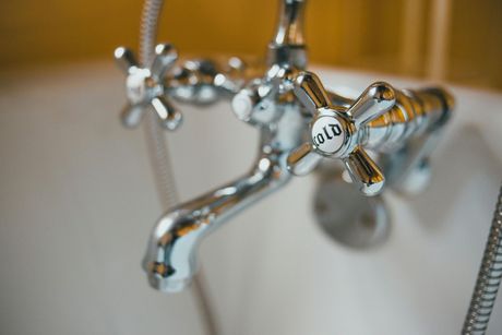 A close-up of a chrome bathroom faucet with two cross-shaped handles, one labeled